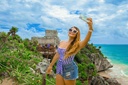 Young woman taking a selfie while enjoying a warm, sunny day at the Tulum ruins in the Riviera Maya.