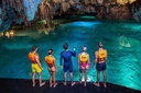 Group of friends admiring the spectacular rock formations and turquoise waters of a cenote in the Riviera Maya.