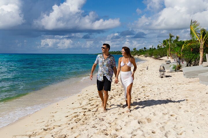 Couple enjoying a stroll on the white sands of an exclusive beach club in the Riviera Maya in the Mexican Caribbean.