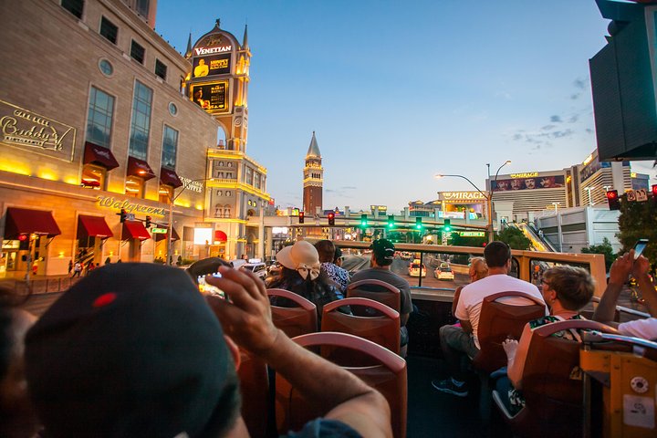 Visitors cruise through Vegas at dusk on a hop-on hop-off bus.